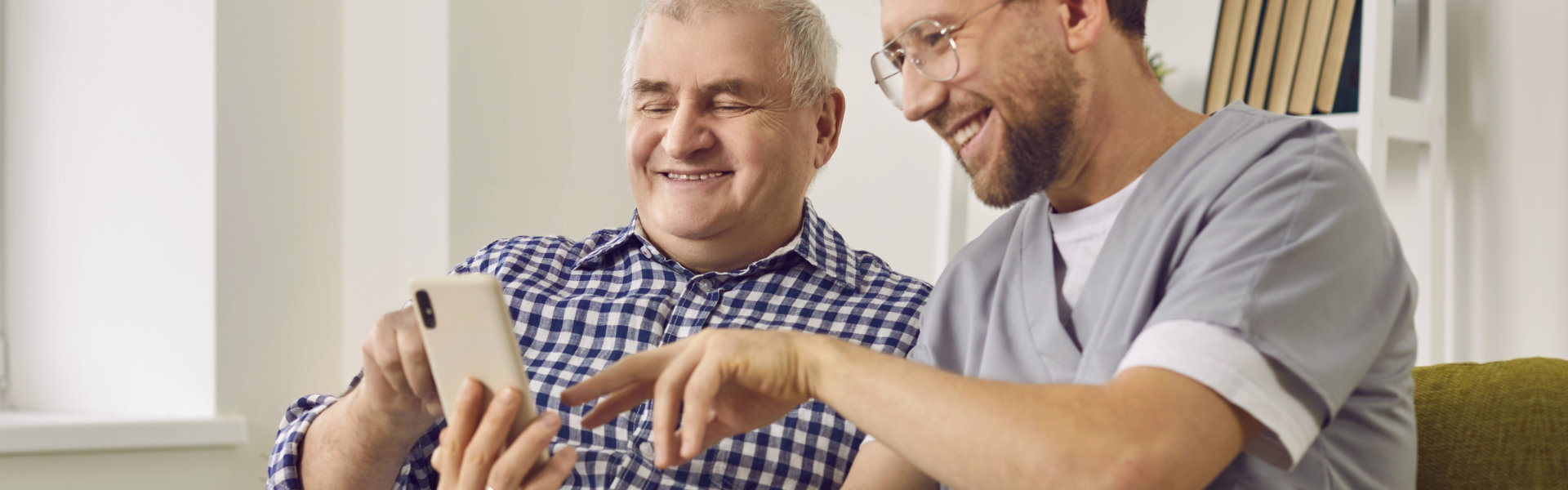 nurse teaching a senior man on how to use a smartphone