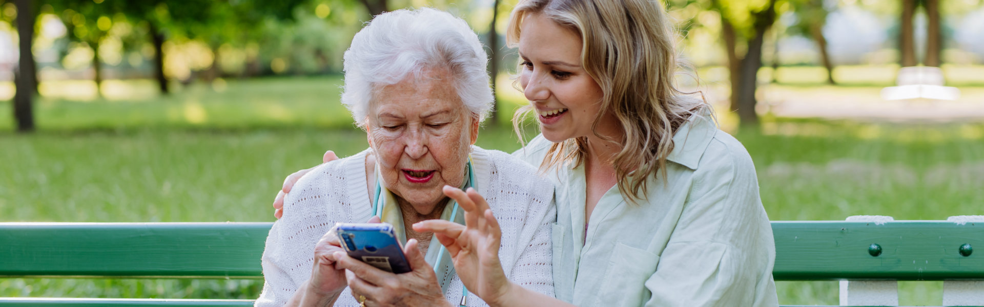 woman teaching a senior woman on how to use a smartphone