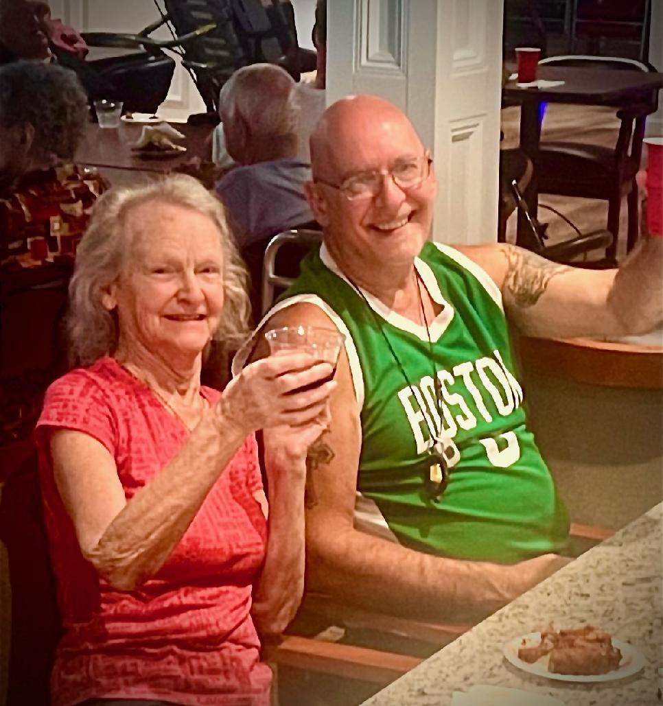 A woman and a man sitting together, smiling and holding drinks.